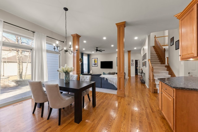 dining area with ceiling fan with notable chandelier, light wood-type flooring, and ornate columns