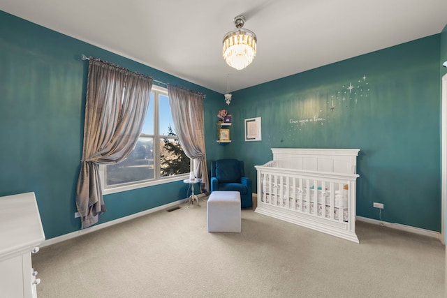 carpeted bedroom featuring an inviting chandelier and a crib