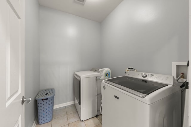 laundry area with separate washer and dryer and light tile patterned floors