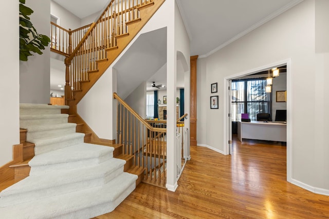 staircase featuring hardwood / wood-style flooring, ceiling fan, ornamental molding, and ornate columns