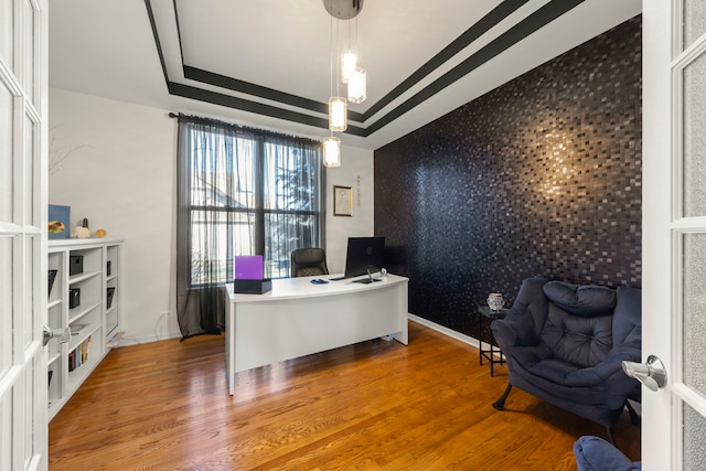 home office featuring a tray ceiling and hardwood / wood-style floors