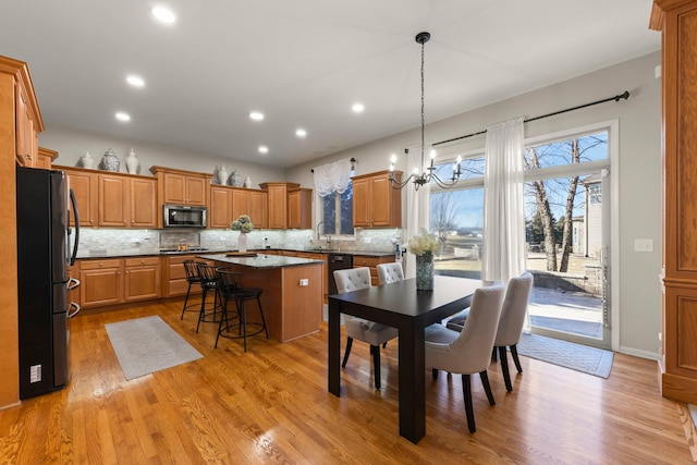 dining room with a chandelier, sink, and light wood-type flooring