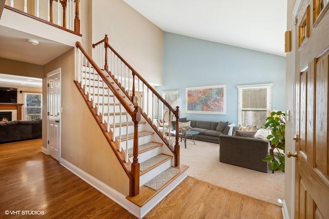 276 Stanton Dr, Buffalo Grove, IL 60089 - staircase featuring a lit fireplace, plenty of natural light, wood finished floors, and high vaulted ceiling