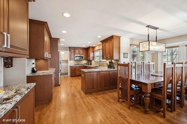 276 Stanton Dr, Buffalo Grove, IL 60089 - kitchen with stainless steel appliances, brown cabinetry, light wood finished floors, tasteful backsplash, and light stone counters