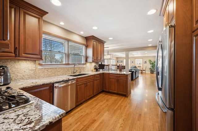 276 Stanton Dr, Buffalo Grove, IL 60089 - kitchen featuring appliances with stainless steel finishes, a peninsula, light wood finished floors, light stone countertops, and decorative backsplash