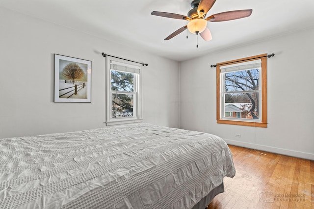 bedroom with ceiling fan, light hardwood / wood-style flooring, and multiple windows