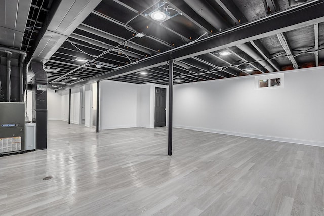 basement featuring hardwood / wood-style flooring and heating unit