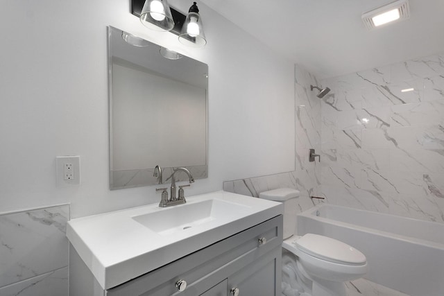 full bathroom featuring toilet, tile walls, tiled shower / bath, and vanity