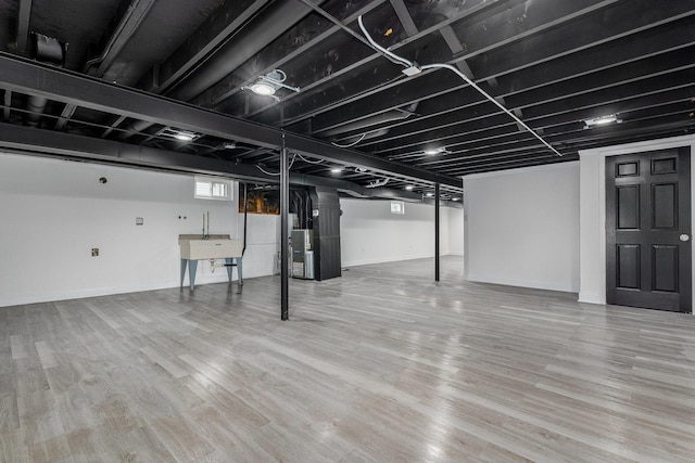 basement featuring heating unit, hardwood / wood-style floors, and sink