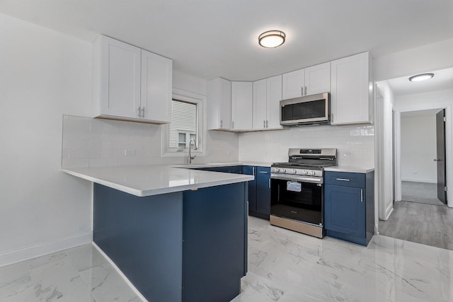 kitchen with kitchen peninsula, sink, appliances with stainless steel finishes, white cabinets, and blue cabinets