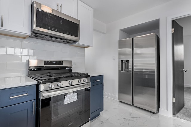 kitchen featuring stainless steel appliances, decorative backsplash, blue cabinets, white cabinets, and light stone counters