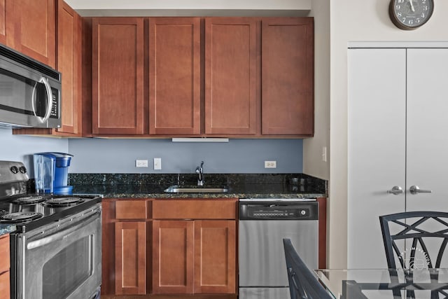 kitchen with appliances with stainless steel finishes, sink, and dark stone countertops