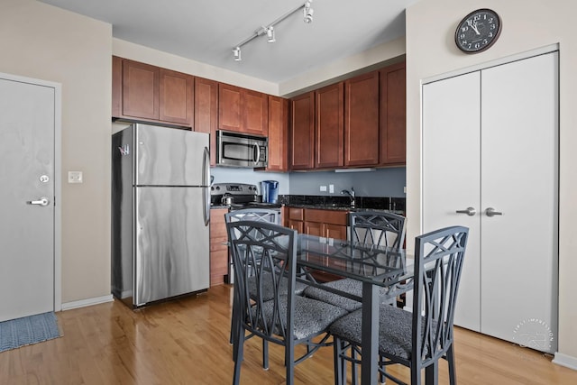 kitchen with sink, track lighting, stainless steel appliances, and light hardwood / wood-style floors