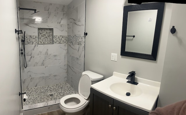 bathroom featuring toilet, vanity, and tiled shower