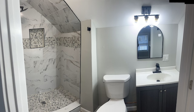 bathroom featuring toilet, vanity, and tiled shower