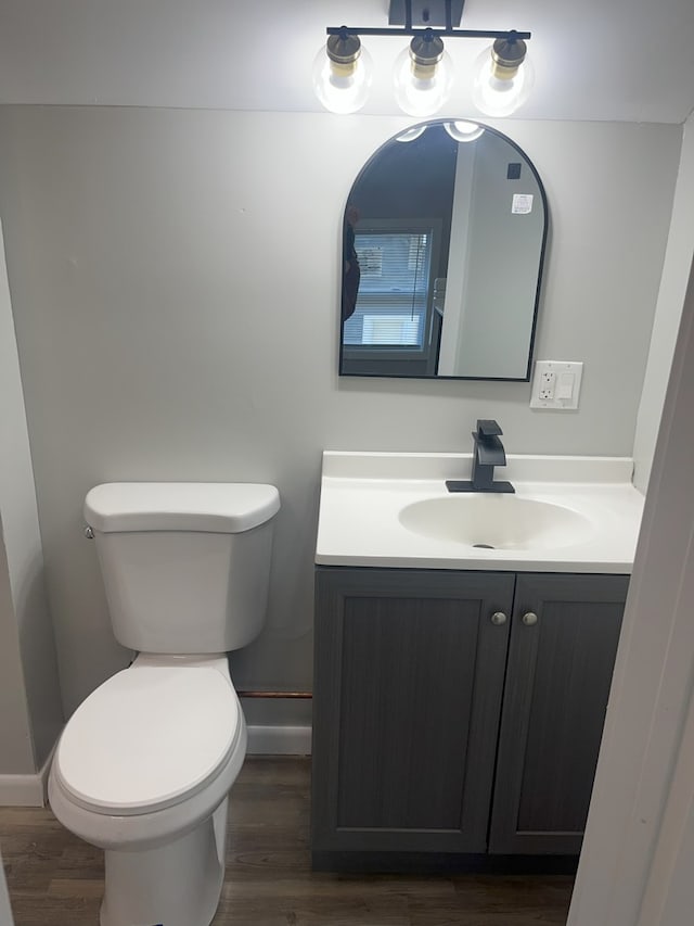 bathroom with toilet, hardwood / wood-style flooring, and vanity