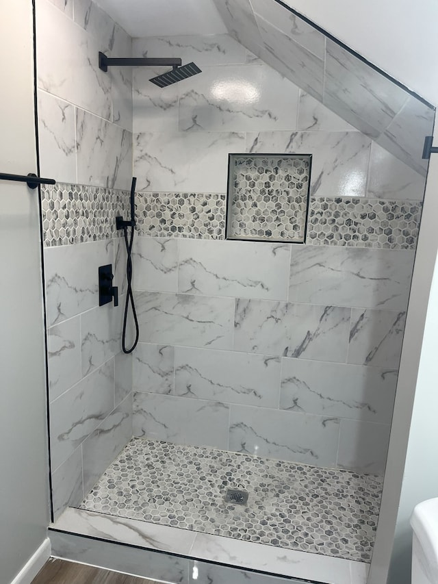 bathroom with a tile shower and hardwood / wood-style floors