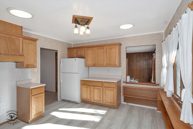 kitchen with ornamental molding, light hardwood / wood-style floors, and white fridge