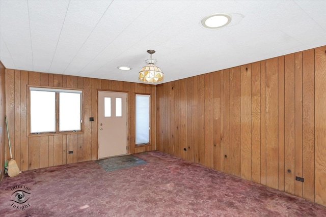 carpeted entrance foyer featuring wooden walls