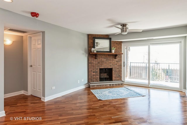 unfurnished living room with hardwood / wood-style flooring, ceiling fan, and a brick fireplace