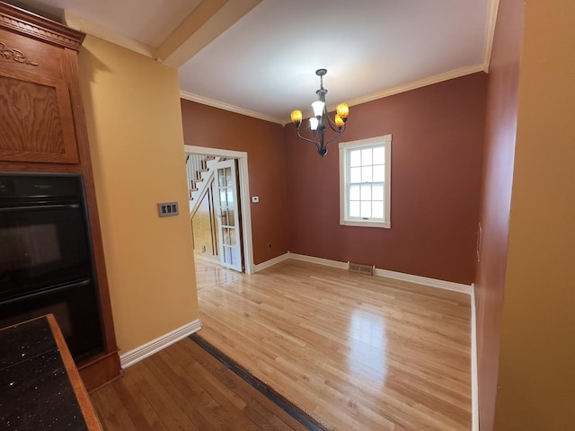 unfurnished dining area featuring a notable chandelier, ornamental molding, and light hardwood / wood-style flooring