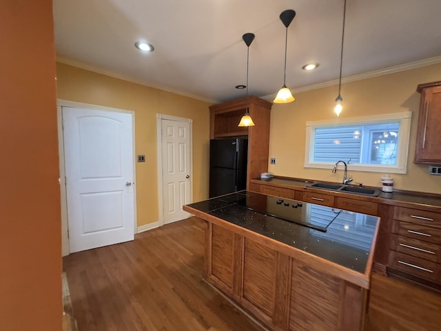 kitchen featuring black refrigerator, dark hardwood / wood-style floors, hanging light fixtures, ornamental molding, and sink