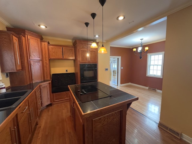 kitchen with hardwood / wood-style floors, decorative light fixtures, a kitchen island, black appliances, and sink