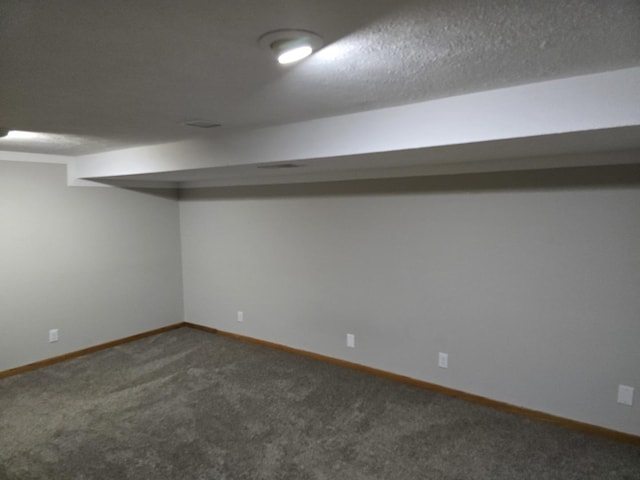 basement with a textured ceiling and dark colored carpet