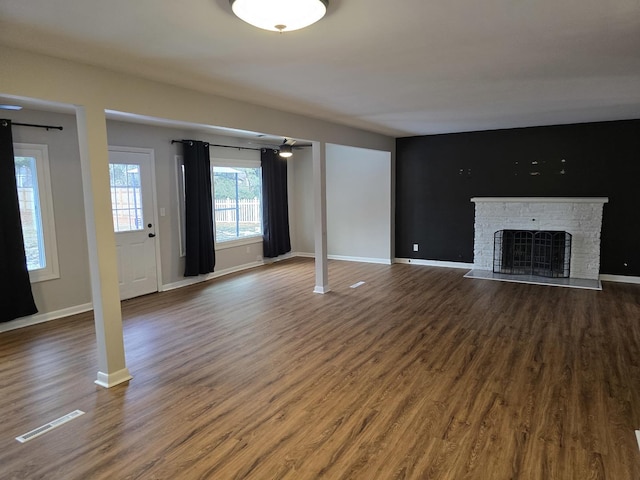 unfurnished living room featuring ceiling fan, a stone fireplace, and dark hardwood / wood-style flooring