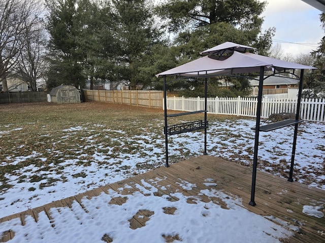 yard covered in snow with a gazebo, a storage shed, and a wooden deck