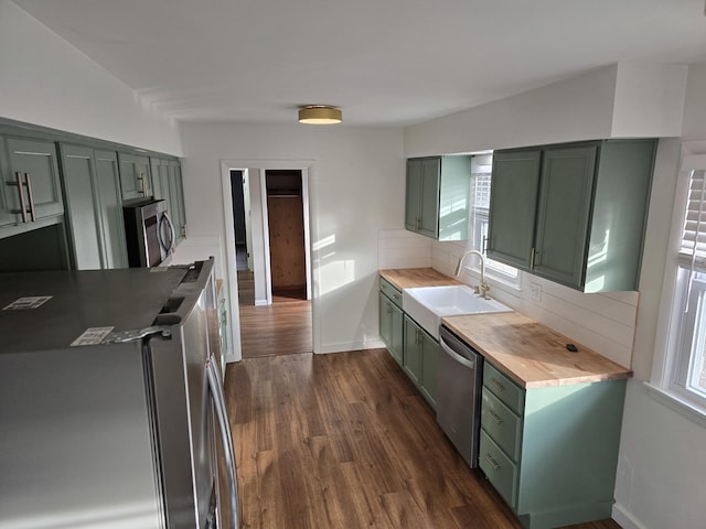 kitchen with green cabinetry, stainless steel appliances, sink, and a wealth of natural light