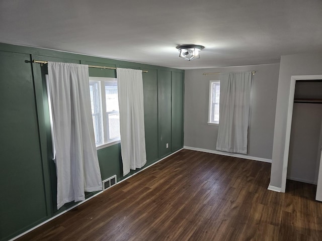 unfurnished bedroom featuring multiple windows and dark wood-type flooring