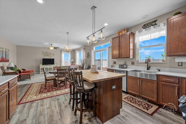 kitchen featuring butcher block countertops, sink, hanging light fixtures, a center island, and stainless steel dishwasher