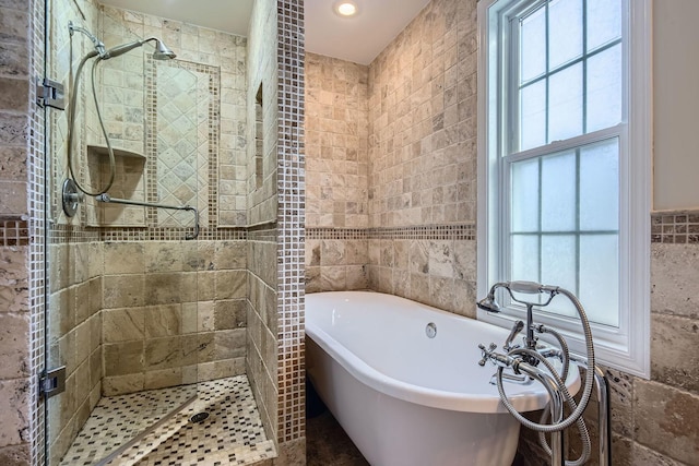 bathroom featuring plus walk in shower and tile walls