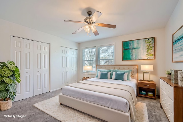 bedroom featuring ceiling fan, light colored carpet, and two closets