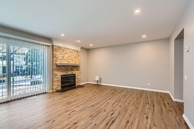 unfurnished living room featuring wood-type flooring and a stone fireplace