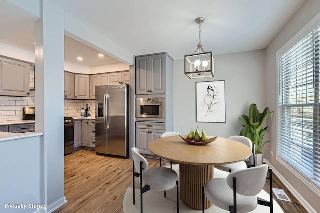 dining area with light hardwood / wood-style floors and an inviting chandelier