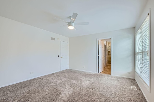 unfurnished bedroom featuring ceiling fan, light colored carpet, and ensuite bath