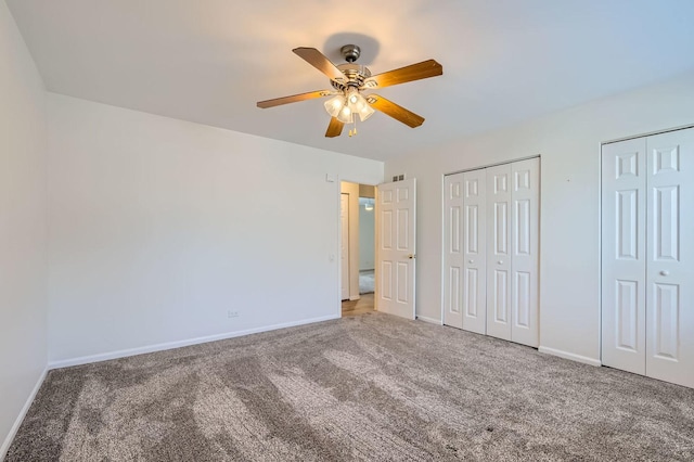 unfurnished bedroom featuring ceiling fan, carpet flooring, and multiple closets