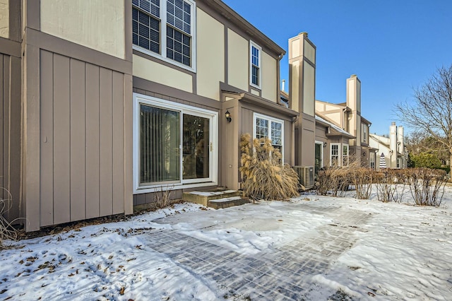 snow covered back of property featuring cooling unit