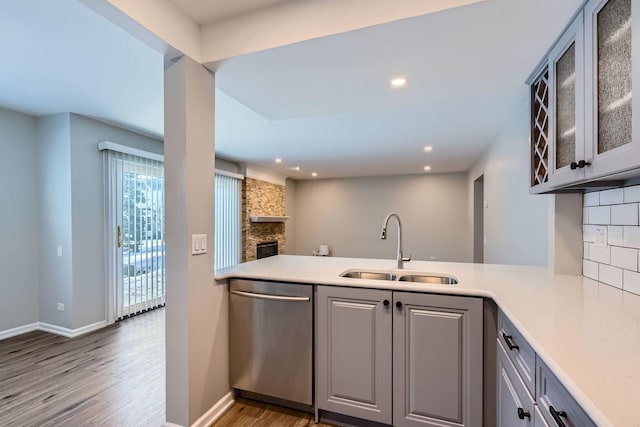 kitchen featuring tasteful backsplash, gray cabinets, stainless steel dishwasher, kitchen peninsula, and sink