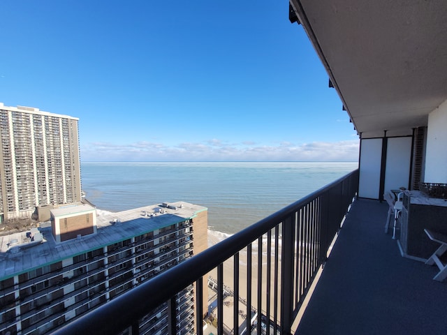 balcony with a water view and a view of the beach