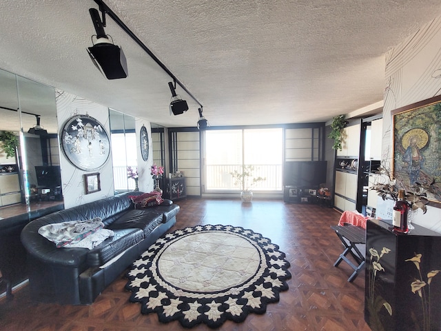 living room featuring track lighting, dark parquet floors, and a textured ceiling