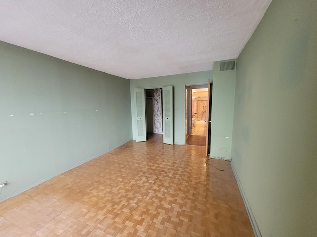 empty room featuring light parquet flooring and a textured ceiling