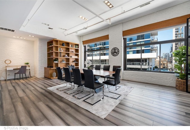 dining space with brick wall and hardwood / wood-style floors