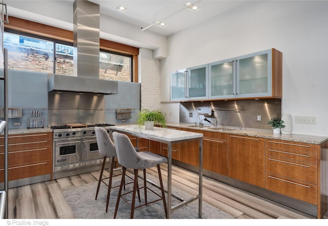 kitchen with double oven range, light stone counters, and tasteful backsplash