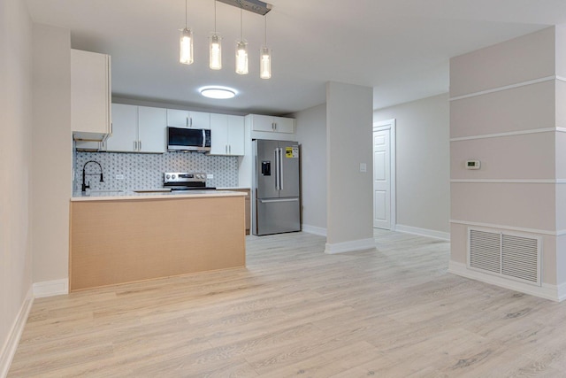 kitchen featuring backsplash, kitchen peninsula, sink, white cabinetry, and stainless steel appliances