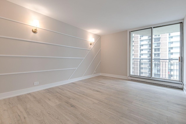 empty room with a baseboard heating unit, a healthy amount of sunlight, and light hardwood / wood-style flooring