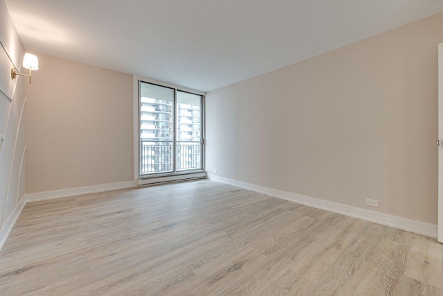 spare room featuring a wall of windows and light hardwood / wood-style floors