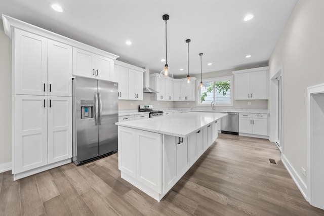 kitchen with appliances with stainless steel finishes, white cabinetry, and a kitchen island